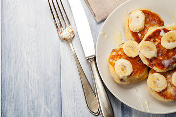 Homemade pancakes with raisins poured on with condensed milk and served with cutted bananas