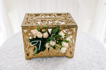 Box for money decorated with flowers stands on the table. Wedding decor.