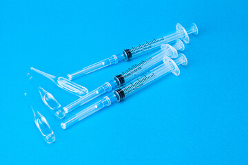 three vaccines for covid in ampoules and syringes lying on blue background