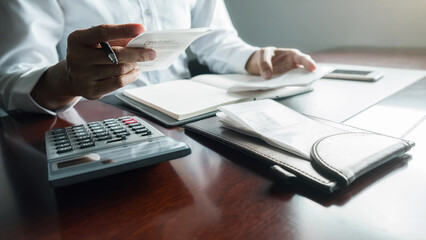 Fototapeta premium Woman with bills and calculator. Woman using calculator to calculate bills at the table in office. Calculation of costs.