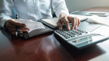 Woman with bills and calculator. Woman using calculator to calculate bills at the table in office....