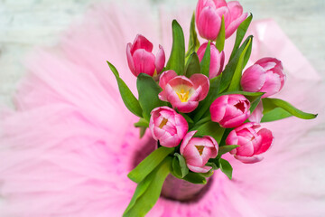 One beautiful bouquet of pink tulips on the pink background. Spring flowers with green leaves