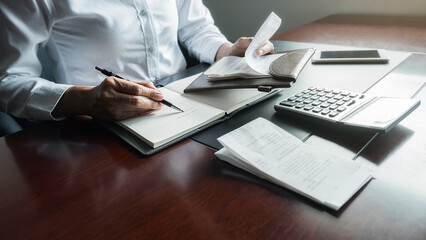 Woman with bills and calculator. Woman using calculator to calculate bills at the table in office....