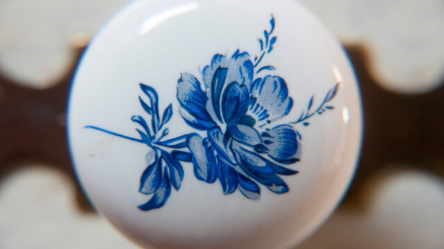 Detalle de flor azul pintada en pomo cer&aacute;mico de mueble antiguo