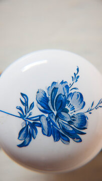 Detalle de flor azul pintada en pomo cer&aacute;mico de mueble antiguo