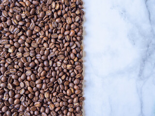The roasted coffee beans on the marble surface. the half-frame of coffee beans. Copy space. Flat-lay or top-down.