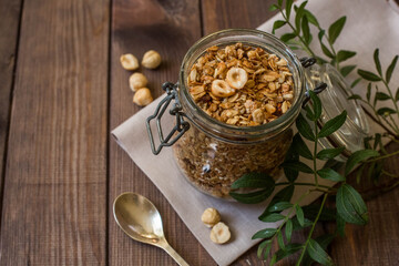 A glass jar with homemade muesli with nuts and a green apple. Healthy breakfast.