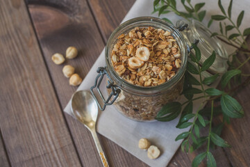 A glass jar with homemade muesli with nuts and a green apple. Healthy breakfast.