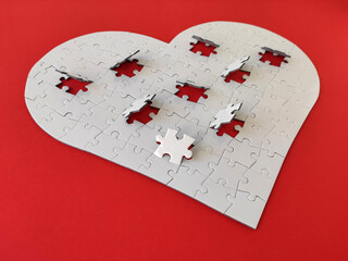 Heart shaped white jigsaw puzzle on red background, puzzle pieces completing the heart shape