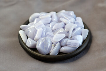 Blue Agate, sapphirine mineral gem stone on black plate and grey cloth as nice background, blue chalcedon