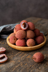 Ripe lychee berries in a plate on a wooden table, selective focus