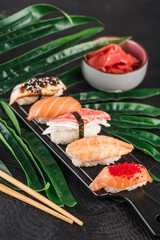 Sashimi sushi set with chopsticks and ginger on a dark background close-up.