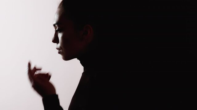 Female silhouette. Respiratory disease. Allergy asthma. Dark contrast profile outline of sick woman with cough wearing protective face mask isolated on white black empty space background.