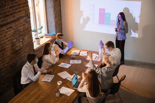 Report. Female speaker giving presentation in hall at university workshop. Audience or conference hall. Co-workers in face masks listening at the table. Scientific, business event, training. High