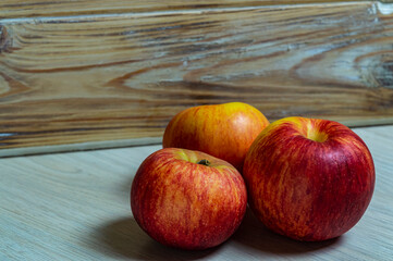 three red apples on a wooden background close-up