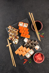 Japanese sushi on a dark background. Sushi rolls, nigiri, maki, pickled ginger, wasabi, soy sauce.