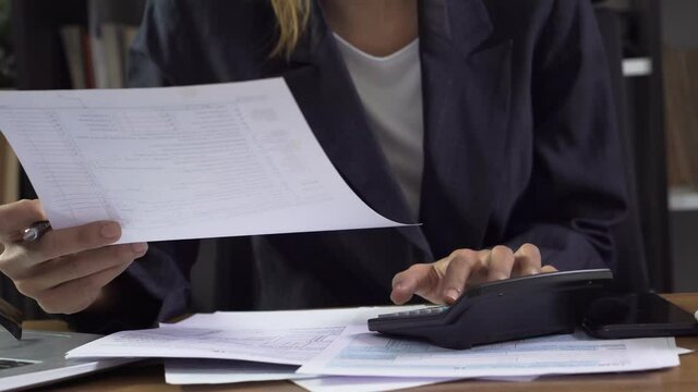 Season to pay Tax, Budget, and Tax planning concept. Business woman wear glasses calculating annual tax and using mobile phone. Calendar 2023 and personal income tax form placed on home office desk.
