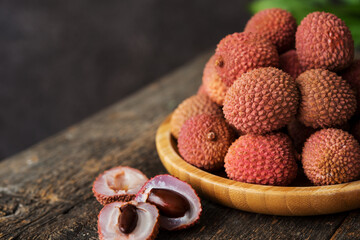 Ripe lychee berries in a plate on a wooden table, selective focus