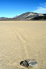 moving stones on the Racetrack Playa leaving tracks in the dry and cracked terrain in the Death Valley National Park, recflections of the sun
