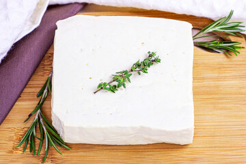 Raw organic vegetarian tofu with fresh rosemary on wooden background.