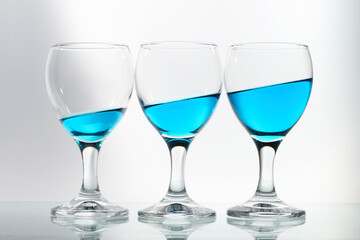 three wine glasses filled with blue fluid side by side