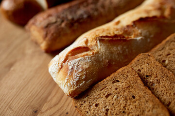 Top view of various kinds of bread on a wooden surface. Close up Concept of homemade bread, small bakery, natural farm products, local food,  domestic production. Healthy and tasty organic food.