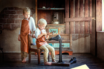 two little brothers in white shirts, aprons and trousers, barefoot repairing shoes