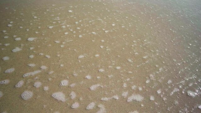 Year 2021 written in the sand at the beach is getting washed away by a sea wave