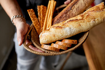 Close yp of man hand, holding basket with various bread freshly baked.