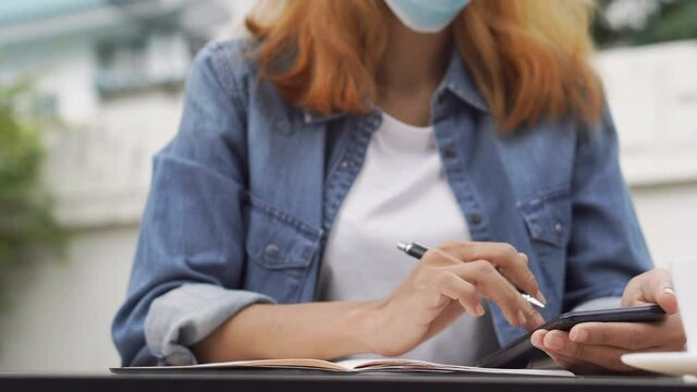 Planner plan and write Schedule Calendar and reminder agenda, work online at home. Close up of woman hand wear mask planning daily appointment and note holiday trip in diary at office desk. 