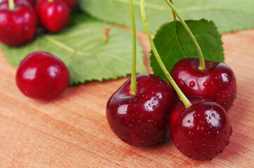 Cherry berries with leaves on a wooden table.
