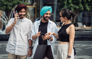 Three excited friends using mobile phone to find sales in the stores