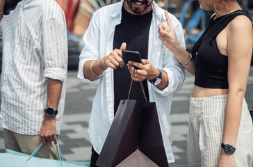 Three unrecognizable friends discuss and looking at mobile phone outdoors