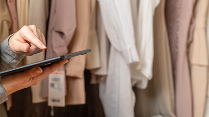 Female entrepreneur holding tablet while doing inventory in her trendy clothing shop