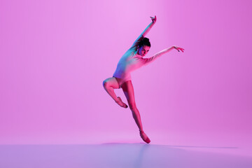 Inspiration. Young and graceful ballet dancer on pink studio background in neon light. Art, motion,...