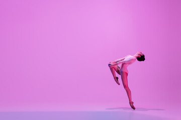 Inspiration. Young and graceful ballet dancer on pink studio background in neon light. Art, motion,...