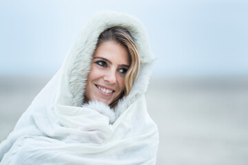 Ritratto di bellissima ragazza bionda che si avvolge un pellicciotto bianco in testa nell'ora del...