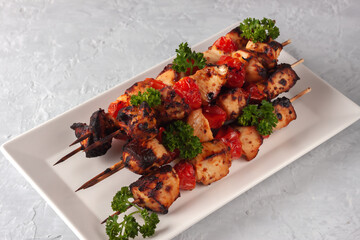 Barbecue of chicken on skewers with vegetables on a gray background