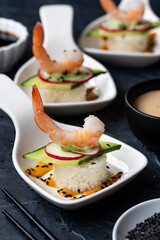 Close up of deconstructed sushi in small white dishes against a dark background.