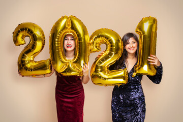 Young women holding 2021 golden balloons during a new year party	