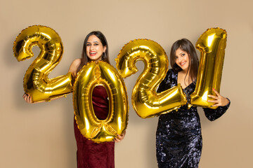 Young women holding 2021 golden balloons during a new year party	