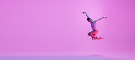 Young and graceful ballet dancer isolated on pink studio background in neon light. Art, motion, action, flexibility, inspiration concept. Flexible caucasian ballet dancer, moves in glow. Flyer - obrazy, fototapety, plakaty