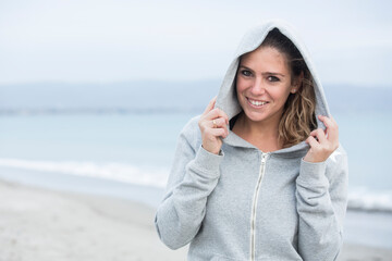 Bellissima ragazza bionda con abbigliamento sportivo, si rilassa in riva al mare tenendosi il...