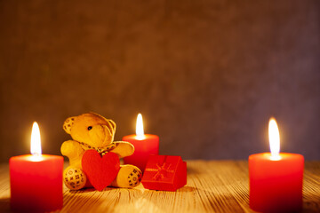 Greeting card on February 14. A teddy bear with a red heart. Three burning red candles. place under the text. Valentine's day background. Copy space.