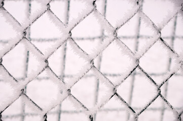 Snow-covered netting in the fence of the sports ground