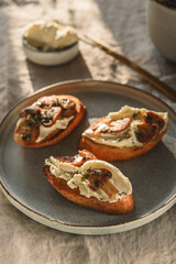 Bruschettas or toasts with cheese and fried mushrooms with thyme on greige linen tablecloth