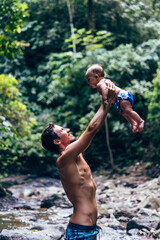 Man playing with his baby son in a natural setting in Costa Rica