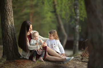 Happy mother with her daughters sitting in the summer forest