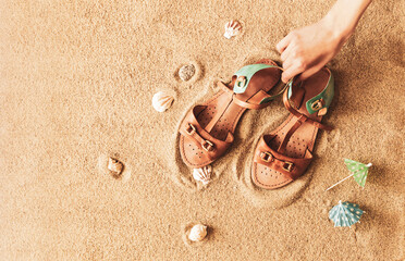 Fototapeta na wymiar Girl’s summer leather boho sandals on the beach - footwear for vacations (holiday).