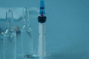 vaccination syringe and vials with medicine close-up on a blue background with a copyspace